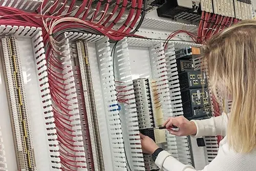 Technician performing electrical installation and wiring inside industrial control panel